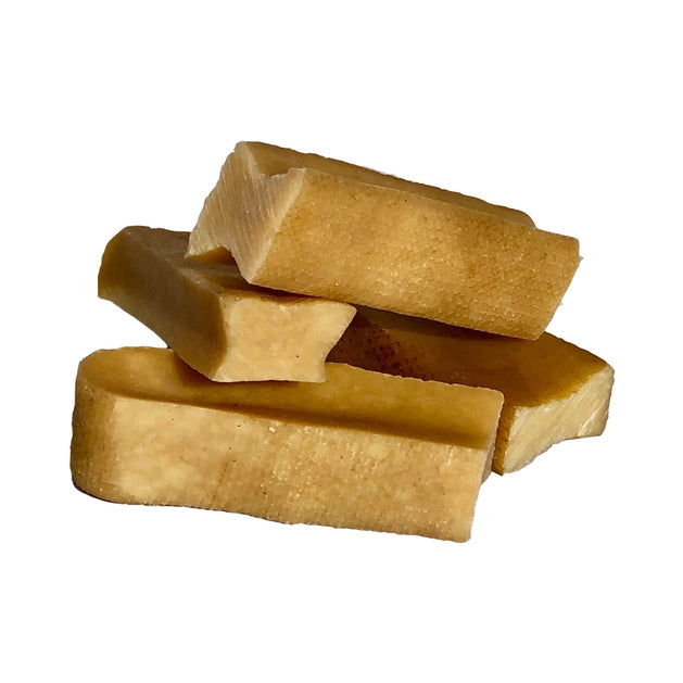 Three golden yak cheese dog chews  stacked in front of a white background