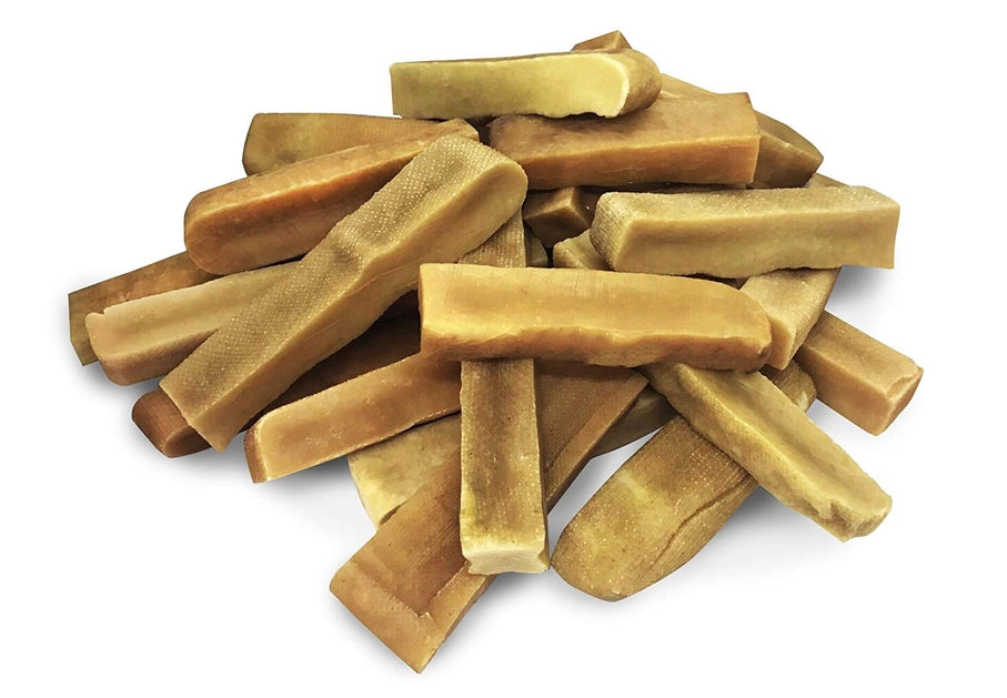Stack of golden dog yak chew treats on a white background