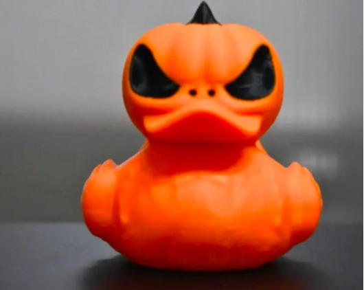 3D Printed Orange rubber duck with a pumpkin design on a gray background