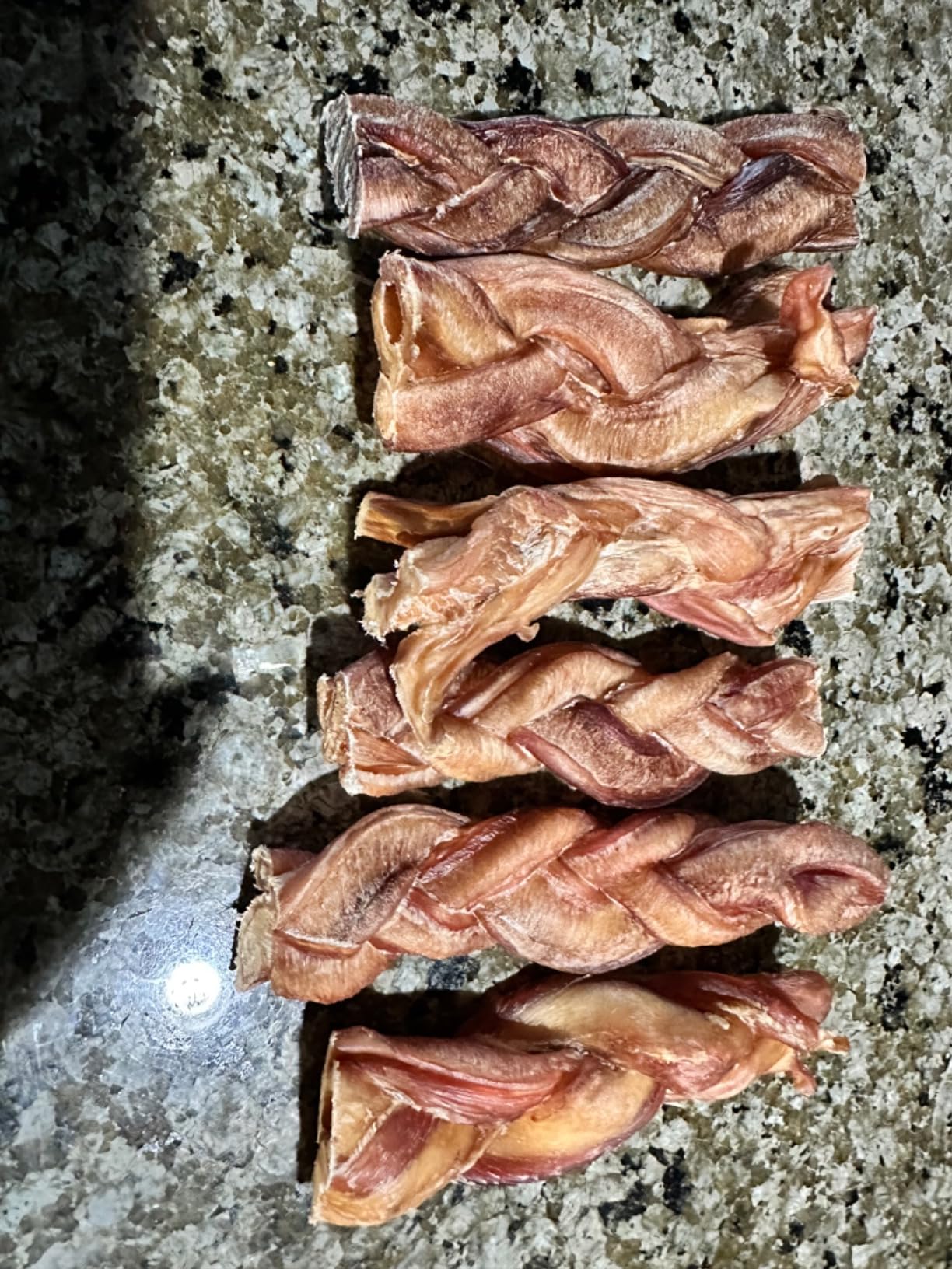 Stack of braided dog treats on a textured surface