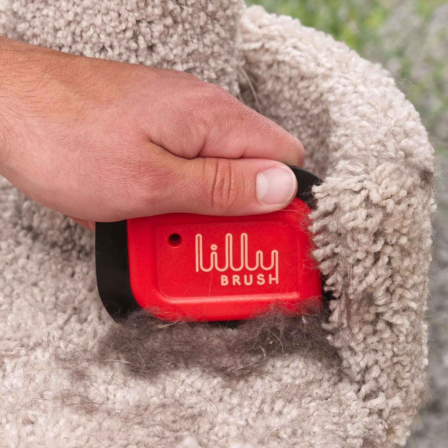Red lillly brush being used on a beige carpet with visible hair removal.